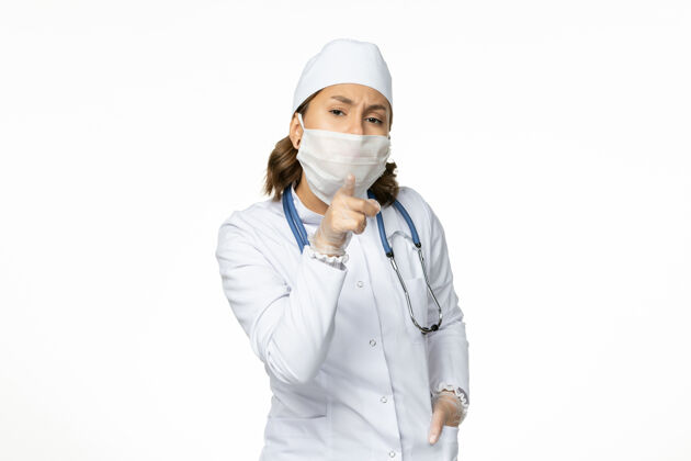 专业正面图年轻女医生穿着白色医疗服 由于白色表面有冠状病毒 戴着口罩医疗医生病毒