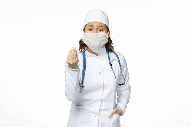 女性正面图年轻女医生穿着白色医疗服 由于白色表面有冠状病毒 戴着口罩听诊器疾病正面