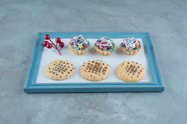 曲奇饼饼干 纸杯蛋糕和圣诞浆果装饰板上的大理石背景高品质的照片甜点美味糕点