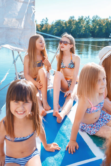 姐妹海上游艇上的孩子们户外蓝天下的少年女孩们五颜六色的衣服孩子们的时尚 阳光明媚的夏天 河流和假日的概念海洋河流人
