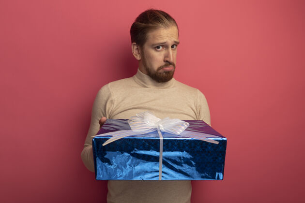 盒子穿着米色套头衫的年轻帅哥手里拿着一个表情悲伤的礼盒站着年轻表情