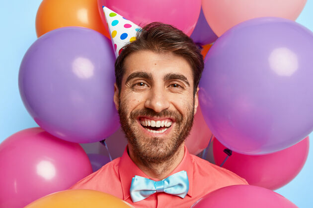活动快乐欧洲男人的头像戴着纸锥帽 粉色衬衫和领结 神采奕奕满意站立男性
