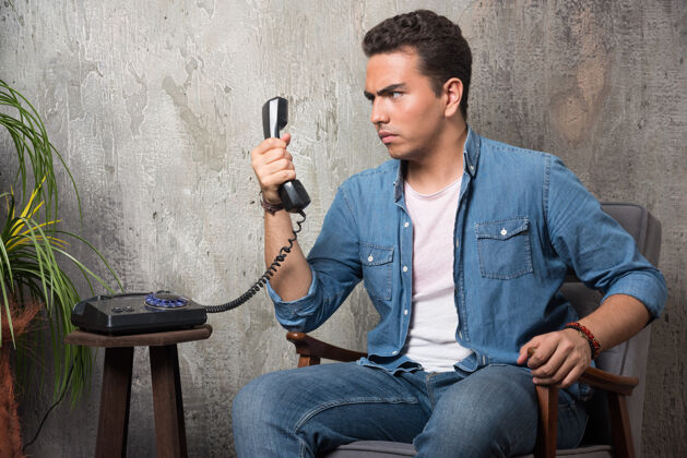 男年轻人看着手机 坐在椅子上高质量的照片男人电话