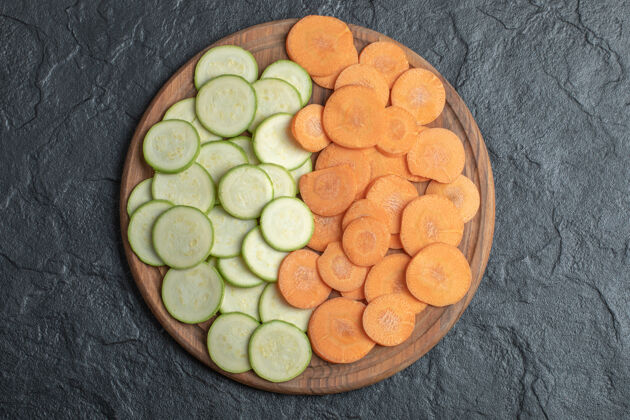 封闭西葫芦和胡萝卜片在黑色背景的木板上高质量的照片食物生的烹饪