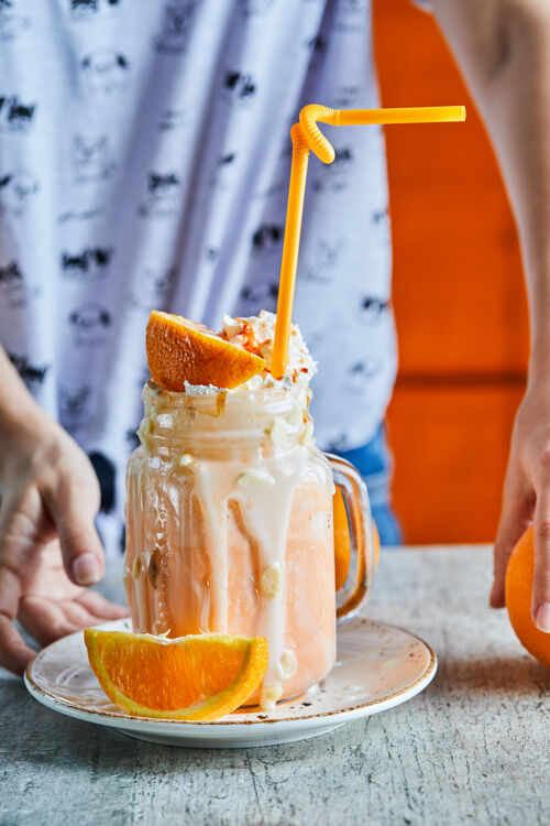 女的一个女人手里拿着一个白色的盘子 上面放着橘子冰沙和橘子片好吃的杯子冰沙