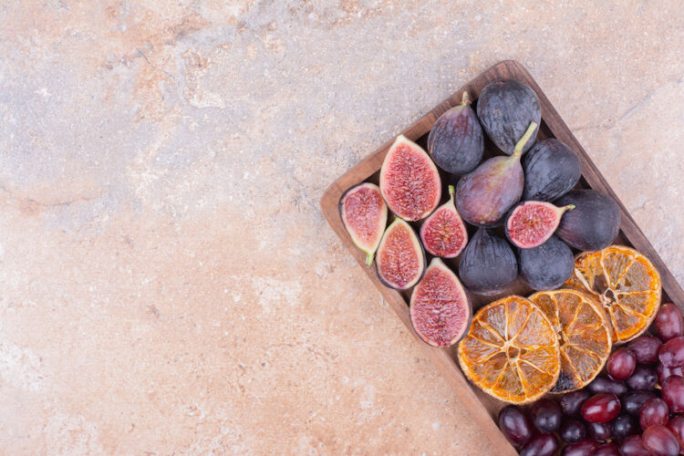 清淡紫色无花果与干燥的橙色切片和山茱萸浆果在木板上产品美味热带