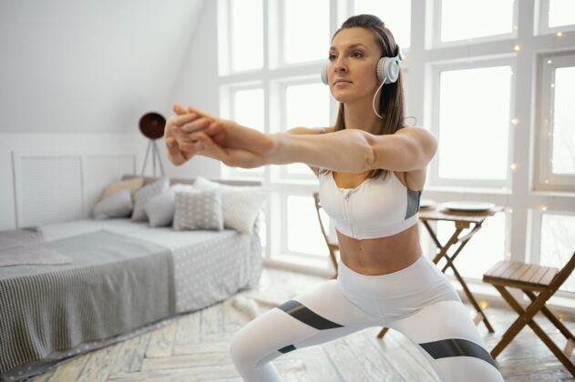 室内女人在家锻炼和听音乐锻炼松紧带房子