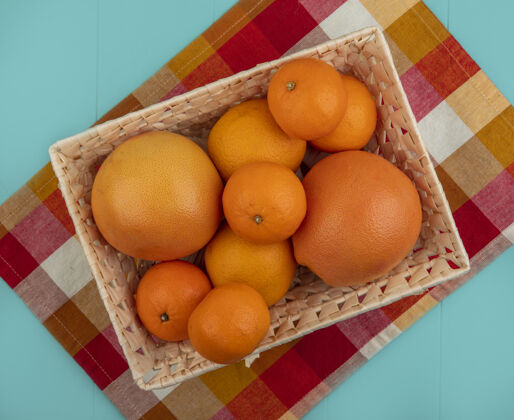 格子上图：蓝绿色背景的格子毛巾上 篮子里放着橘子和葡萄柚绿松石水果风景