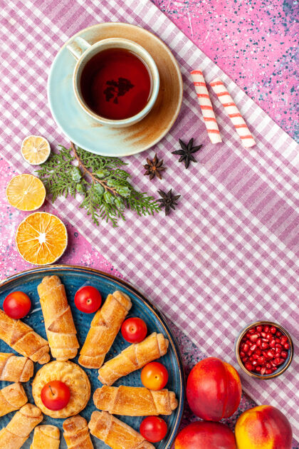 派顶视图甜美美味的百吉饼在托盘内与李子新鲜桃子和一杯茶在淡粉色的桌子上餐甜食浅粉色