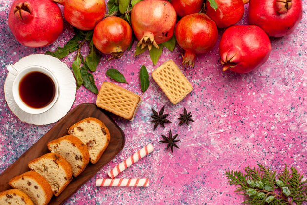 农产品在粉红色的桌子上 可以俯瞰新鲜的红石榴 切片蛋糕华夫饼和一杯茶蔬菜果汁萝卜