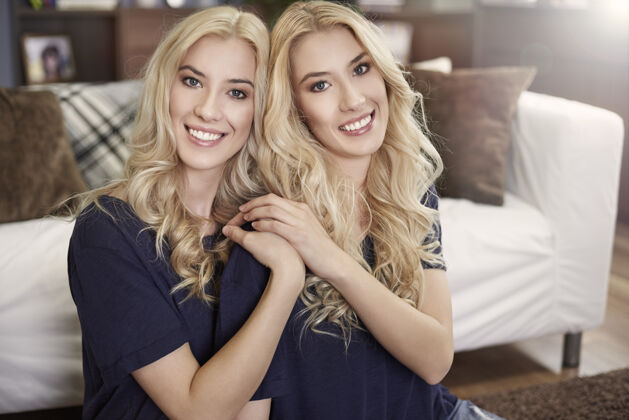 享受美丽的金发姐妹的画像在一起休闲两个人