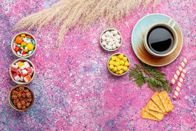 刺绣在粉红色的桌子上可以看到一杯茶 里面放着饼干和糖果放松邦邦杯子