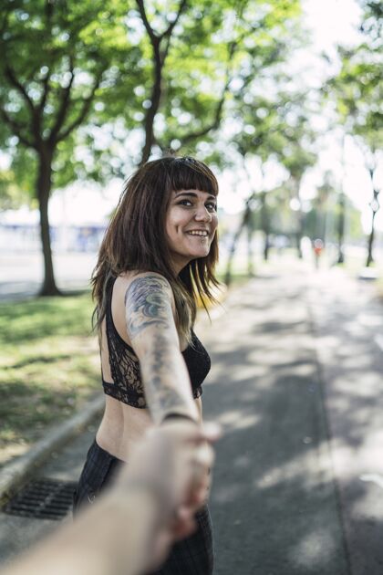 吸引力年轻迷人的白种女人站在公园里纹身 做一张可爱的脸纹身成人皮肤
