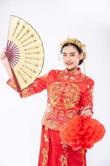 中国新年穿旗袍西服的女士手持中国手扇和红灯 在中国新年的大型活动中亮相微笑欢呼传统服装
