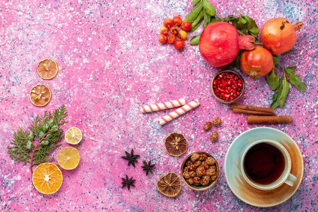 树叶顶视新鲜石榴与绿叶和茶杯浅粉红色的表面装饰品食品新鲜