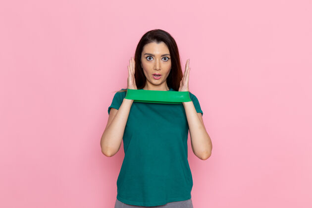 运动正面图年轻女性拿着绿色绷带在粉红色的墙上锻炼运动锻炼运动员腰部美丽视图漂亮可爱