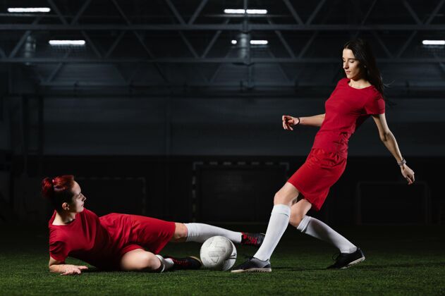 足球场两个女足球运动员运动足球足球服