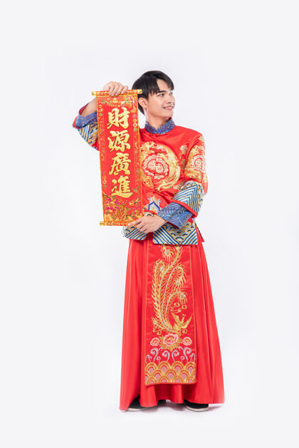男孩穿旗袍西服 穿黑鞋的男人在中国新年给家人送上中国贺卡祝好运成人中国文化团结