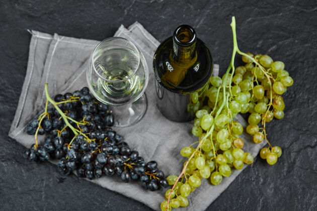 优雅混合葡萄 一杯葡萄酒和一瓶灰色桌布在黑暗的表面健康酒多汁