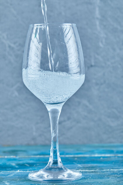 新鲜的一杯蓝色表面的起泡水倒的提神玻璃