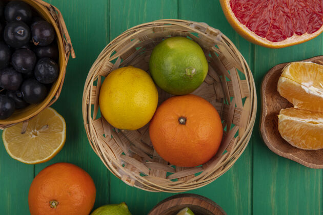 橙色顶视图樱桃李子放在篮子里 柠檬橙和酸橙放在绿色背景的篮子里柠檬风景李子