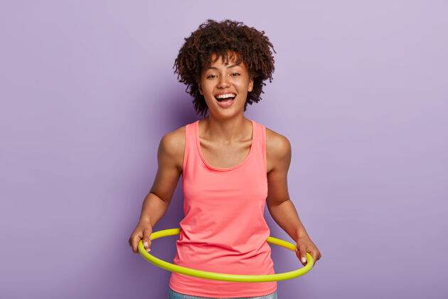 运动照片中乐观的黑皮肤女子旋转呼啦圈 旨在拥有完美的腰部精力充沛健身房秋千