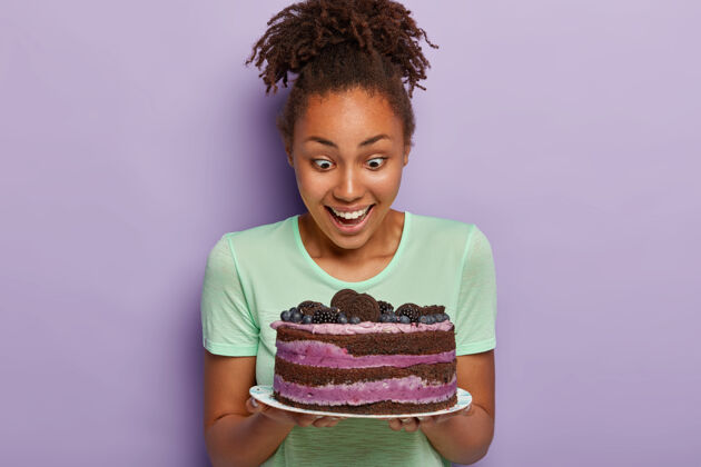 射击健康黑皮肤的可爱女人 幸福地盯着盘子里美味的水果蛋糕喜悦面包房盘子
