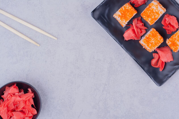 食物黑色陶瓷盘中的鲑鱼寿司卷筷子质量盘子
