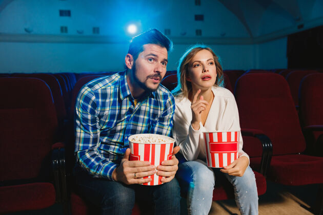 划船迷人的年轻白种人夫妇在电影院 房子或电影院看电影看起来富于表现力 惊讶和情绪化独自坐着玩关系 爱情 家庭 周末时间娱乐大厅男