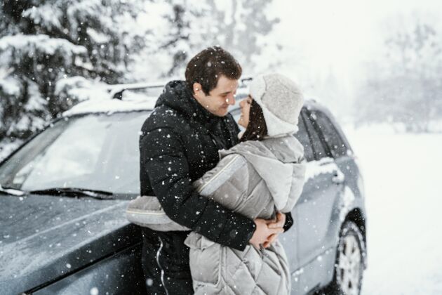 女人浪漫情侣在雪地里接吻的侧视图接吻户外男人