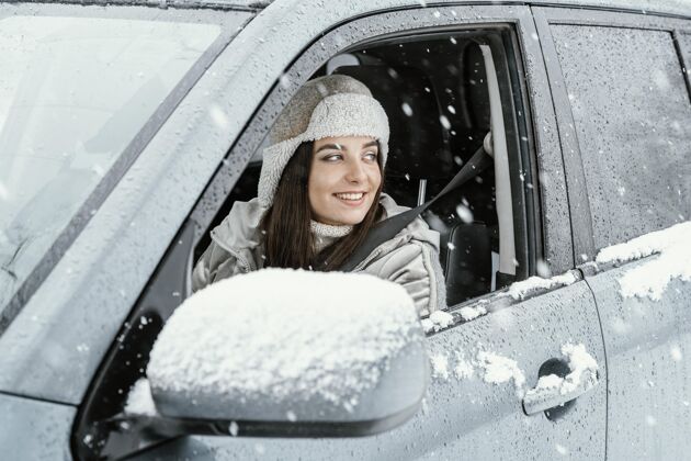 汽车侧视图笑脸女子驾驶的汽车在公路旅行雪冒险冬天