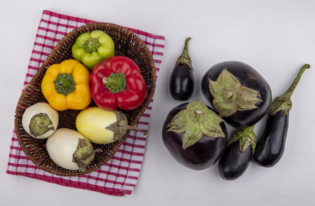 茄子顶视图白色茄子与彩色甜椒在一个篮子上红色方格毛巾与黑色茄子在白色背景黑格子食物
