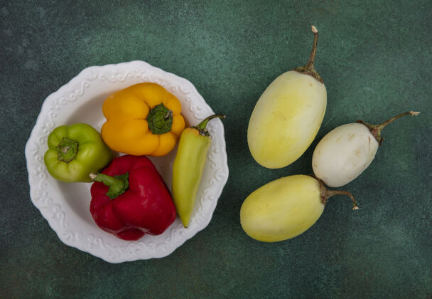 白的顶视图白色茄子和青椒放在一个盘子里 背景是绿色的胡椒绿的食物