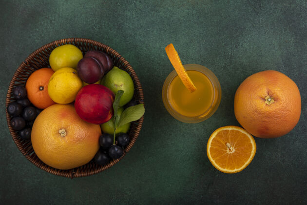 柠檬在绿色的背景下 一个篮子里放着葡萄柚 酸橙 柠檬 桃子 樱桃 李子 橘子和李子饮料果汁篮子