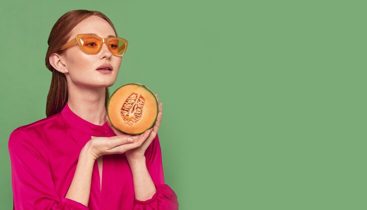 吃美丽的红发女人拿着一个甜瓜复制空间肖像饮食构图
