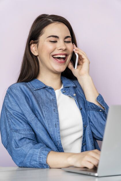 世界欢笑日快乐的女人在电话里交谈和使用笔记本电脑的画像垂直全球庆祝