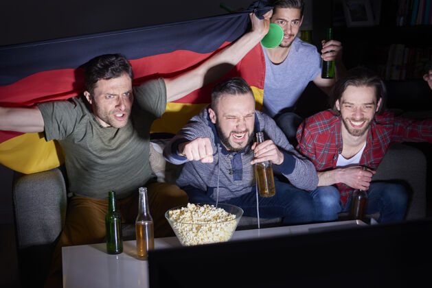 兴奋男人们在电视上看冠军赛足球支持观众