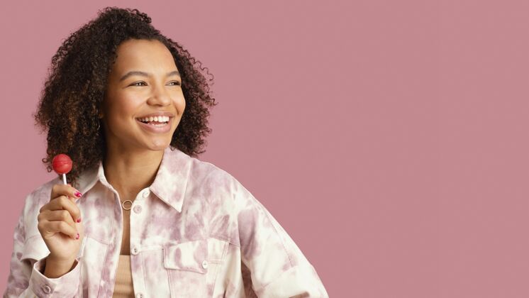 非裔美国人笑脸女人与棒棒糖和复制空间的正面视图年轻黑人妇女美丽
