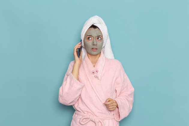 尺子正面图年轻女性穿着粉色浴袍淋浴后在浅蓝色墙上讲电话美容水自理淋浴干净成人清洁女