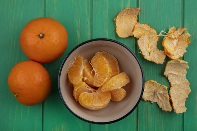 视图顶视图橙子与果皮在一个绿色的背景碗碗水果彩色