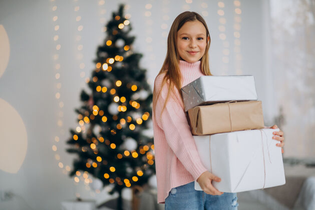 孩子可爱的女孩拿着圣诞礼物在圣诞树旁美丽微笑快乐的女孩