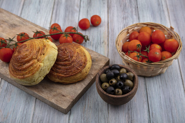 成熟阿塞拜疆传统糕点的俯视图在木制厨房板上 成熟的葡萄藤西红柿和橄榄放在木制碗上 灰色木制背景顶部团队足球