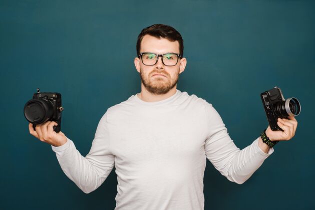 抱着戴眼镜的男人拿着一个旧相机和一个新相机 想着选哪一个年轻的脸男人
