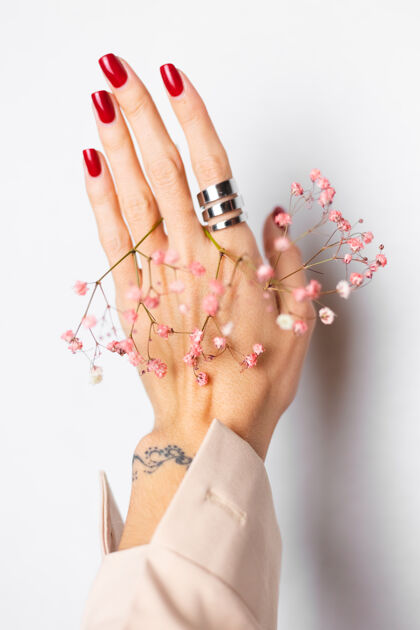 叶柔美温柔的照片 女人手上戴着大戒指 红色的指甲 手上拿着可爱的粉色干花园艺花店开花