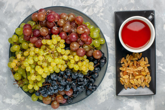 葡萄顶视图新鲜葡萄与一杯茶和葡萄干的白色表面水果新鲜茶葡萄观点可食用水果生的