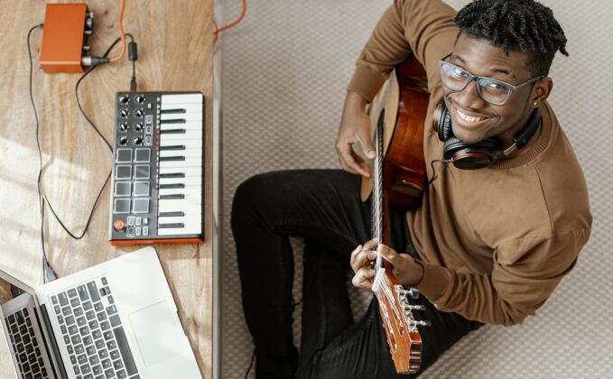 表演笑脸男音乐家顶视图在家里弹吉他和笔记本电脑混合男人娱乐艺术家