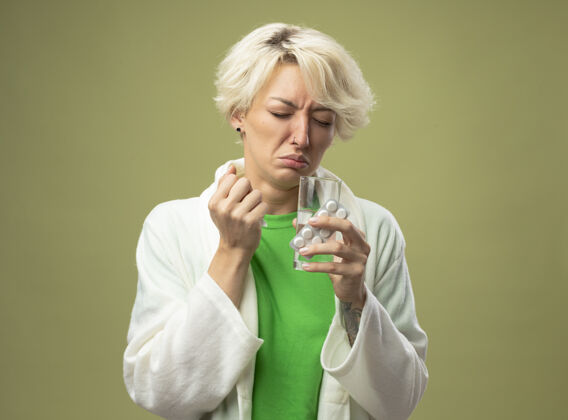 女人一个短发女人站在光墙上 手里拿着一杯水 手里拿着药丸 身体不舒服光水泡头发