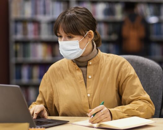学习戴着口罩的学生在图书馆学术学习学校