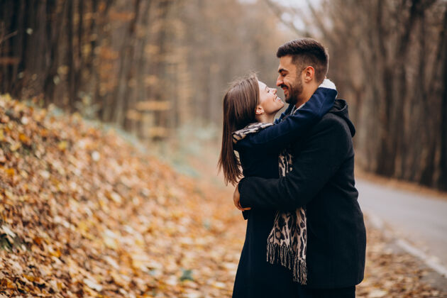 快乐的女人一对年轻夫妇在秋天的公园里散步浪漫男朋友年轻