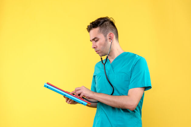 专业黄色墙上的男医生的正视图 带分析和听诊器英俊健康医院
